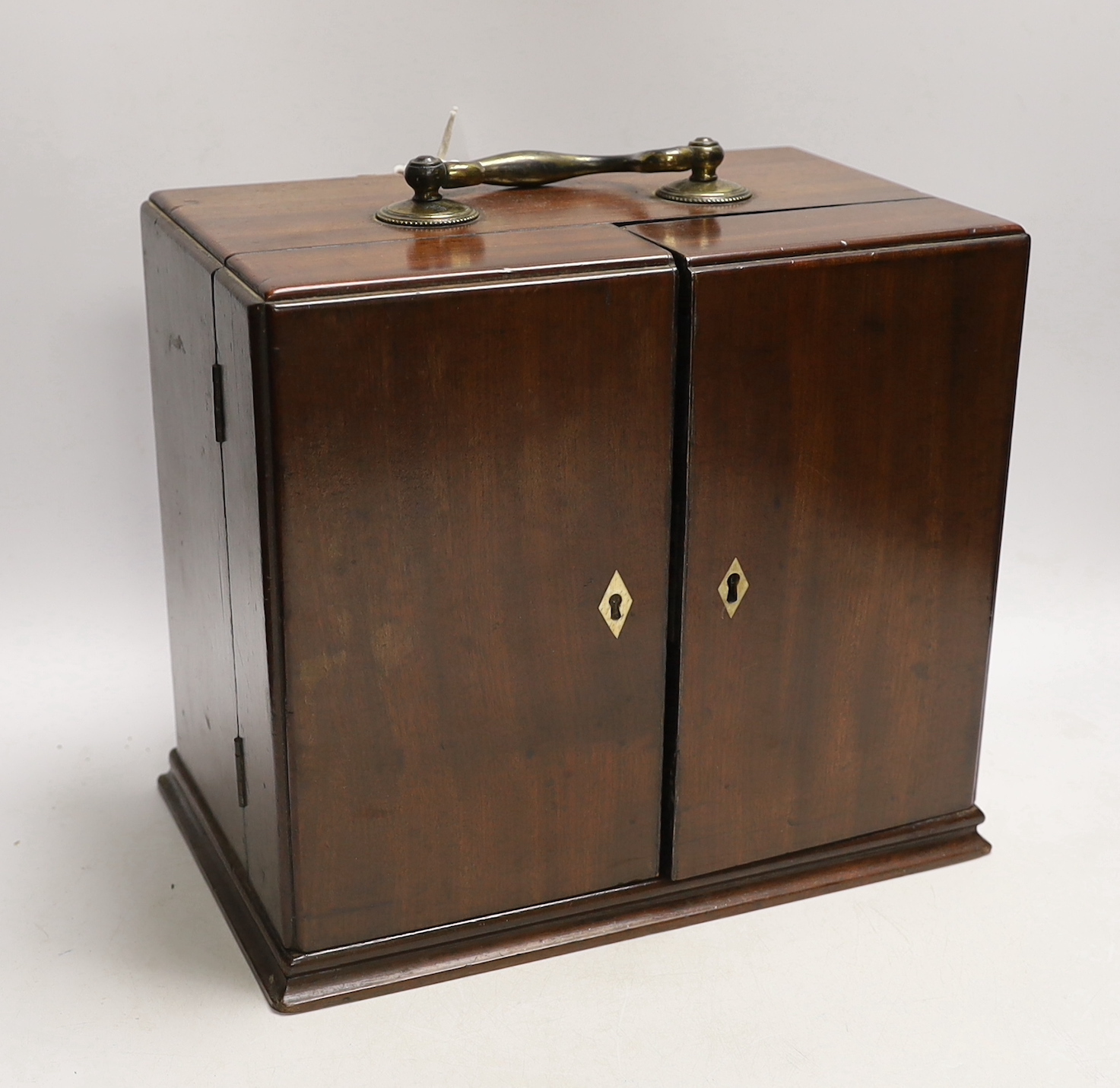 A Georgian mahogany domestic medicine chest, with bone drawer knobs and escutcheons, containing a number of glass square section drug bottles, fitted drawers containing scales, a pestle and mortar, etc., 29cm wide, 25cm